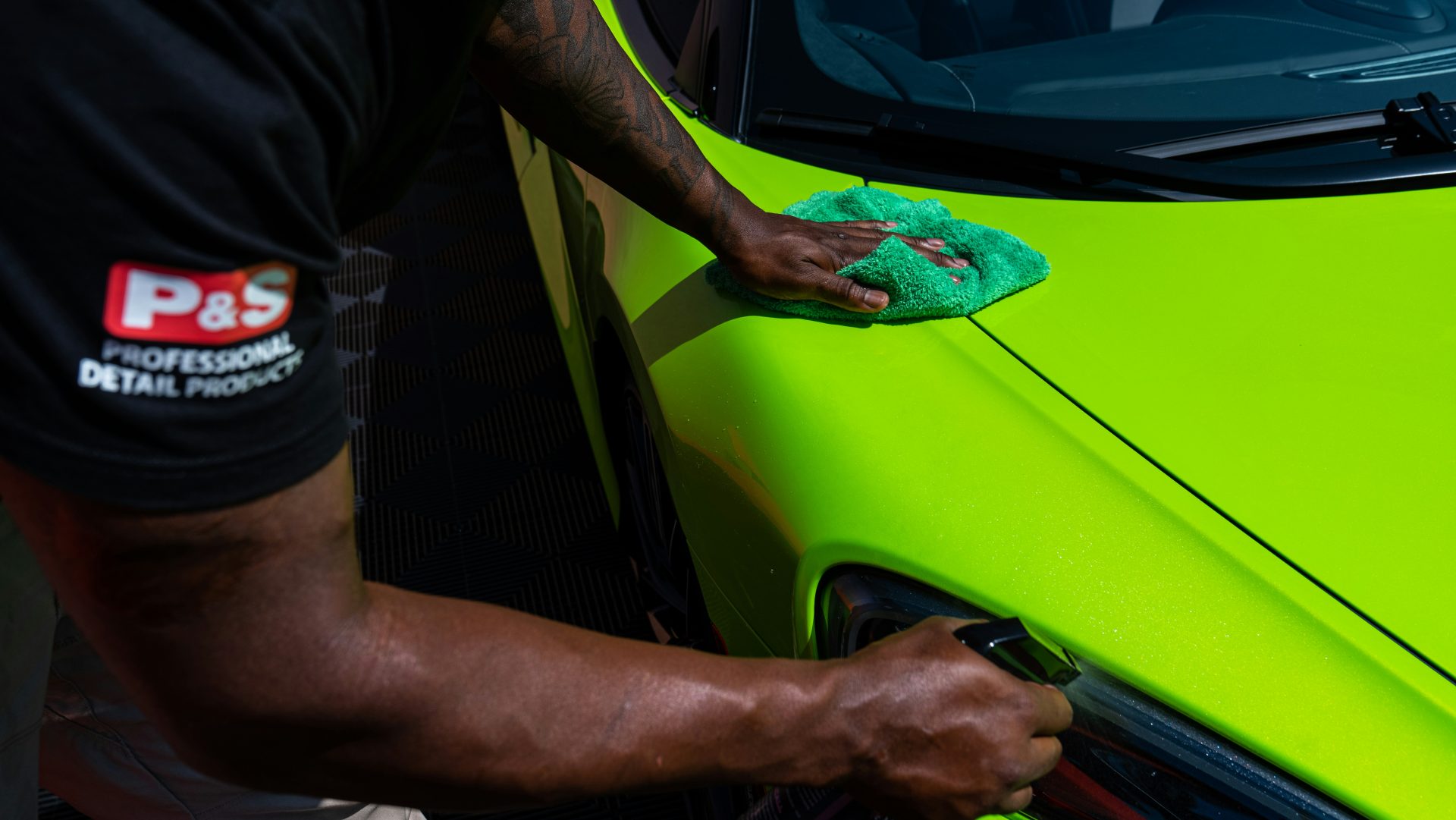 a man polishing the side of a green sports car